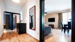 Moderni hotellihuone, jossa on puulattia, suuri peili, sänky, televisio ja ruokailutila.