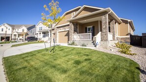 A residential house with a stone facade, a front porch, and a well-maintained lawn.