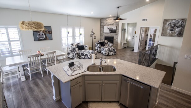 A modern kitchen with a central island, white dining area, and a fireplace.