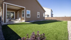 A modern house with a covered patio, a well-maintained lawn, and a wooden fence.