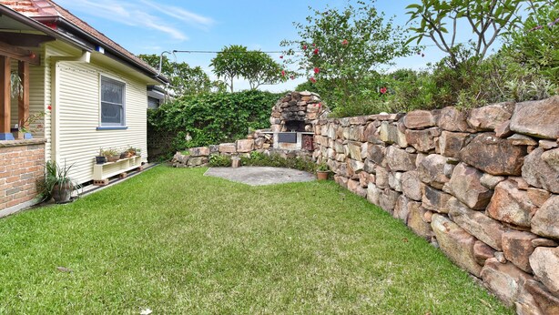 A house with a stone wall, a small garden, and a brick chimney. - Wangi Waterfront Hideaway (Wangi Wangi)