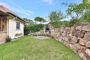 A house with a stone wall, a small garden, and a brick chimney.