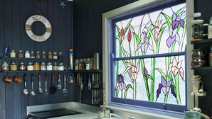 A kitchen with a stove, sink, and various utensils hanging on the wall. - Wangi Waterfront Hideaway (Wangi Wangi)