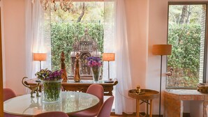 A dining area with a glass table, pink chairs, and a vase of flowers. There is a statue on the table and a lamp on a side table. - Beautiful townhouse with garden, communal pool in Calpe, 4 km from the beach. (CALPE)