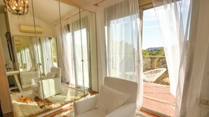 A modern living room with a white armchair, a large mirror, and a view of a balcony with outdoor furniture. - Beautiful townhouse with garden, communal pool in Calpe, 4 km from the beach. (CALPE)