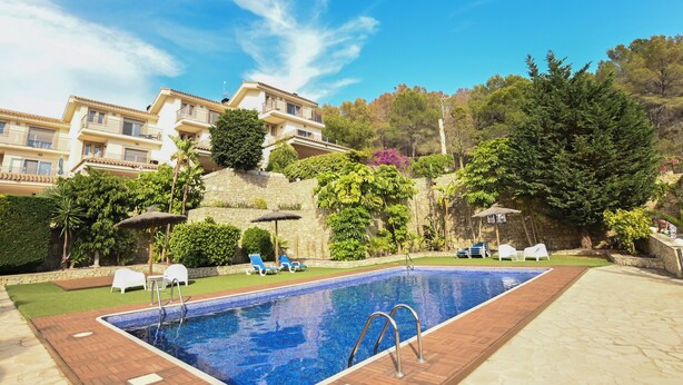 A swimming pool with lounge chairs and a stone wall in the background. - Beautiful townhouse with garden, communal pool in Calpe, 4 km from the beach. (CALPE)