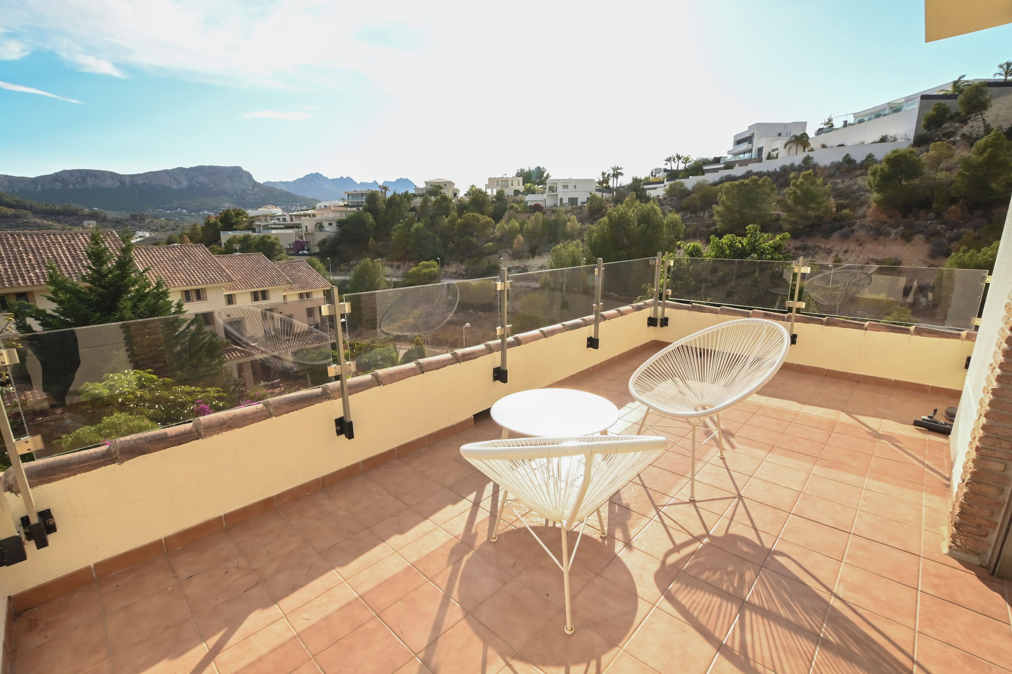 Terraza en la azotea con mesa y sillas, y vistas de los edificios y el paisaje circundantes.