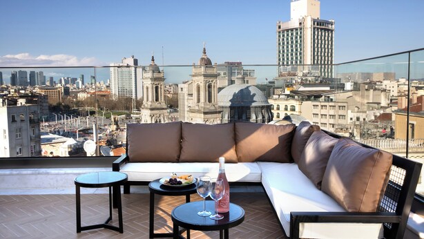 A rooftop terrace with a sofa, two small tables, and a bottle of wine. - The Trinity Hotel Taksim - Special Class (Istanbul)