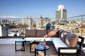 A rooftop terrace with a sofa, two small tables, and a bottle of wine. - The Trinity Hotel Taksim - Special Class (Istanbul)