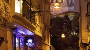 A historic building with a bell tower, a gated entrance, and a lit-up signboard. - The Trinity Hotel Taksim - Special Class (Istanbul)