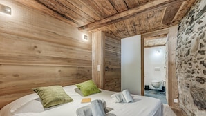 A wooden cabin room with a bed, pillows, and towels. - Rustic chalet for 12, 5 rooms, Wifi in Tignes (Tignes-Les Brévières)