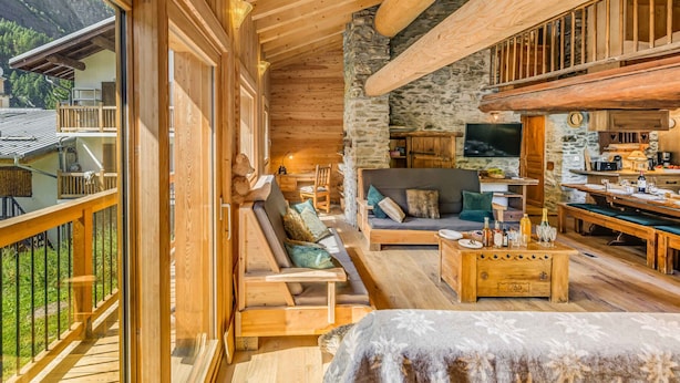A cozy wooden cabin with a stone wall, a balcony, and a dining area. - Rustic chalet for 12, 5 rooms, Wifi in Tignes (Tignes-Les Brévières)