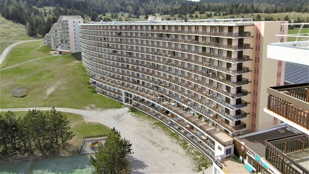 A large, multi-story hotel with numerous balconies and a curved structure. - Cozy Studio for 3 with Free WiFi, Close to Slopes & Shops, Private Ski Locker, Parking Available (Le Dévoluy)