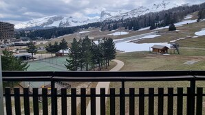 A view from a balcony overlooking a mountainous landscape with snow-covered peaks, a ski slope, and a small building in the foreground. - Cozy Studio for 3 with Free WiFi, Close to Slopes & Shops, Private Ski Locker, Parking Available (Le Dévoluy)