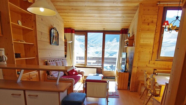 A cozy wooden cabin with a sofa, dining table, and kitchen area.