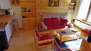 A cozy living room with a wooden sofa, a coffee table, and a dining area with a wooden table and chairs.
