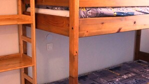 Ein Etagenbett mit Holzrahmen und einer Matratze mit gemustertem Bezug.