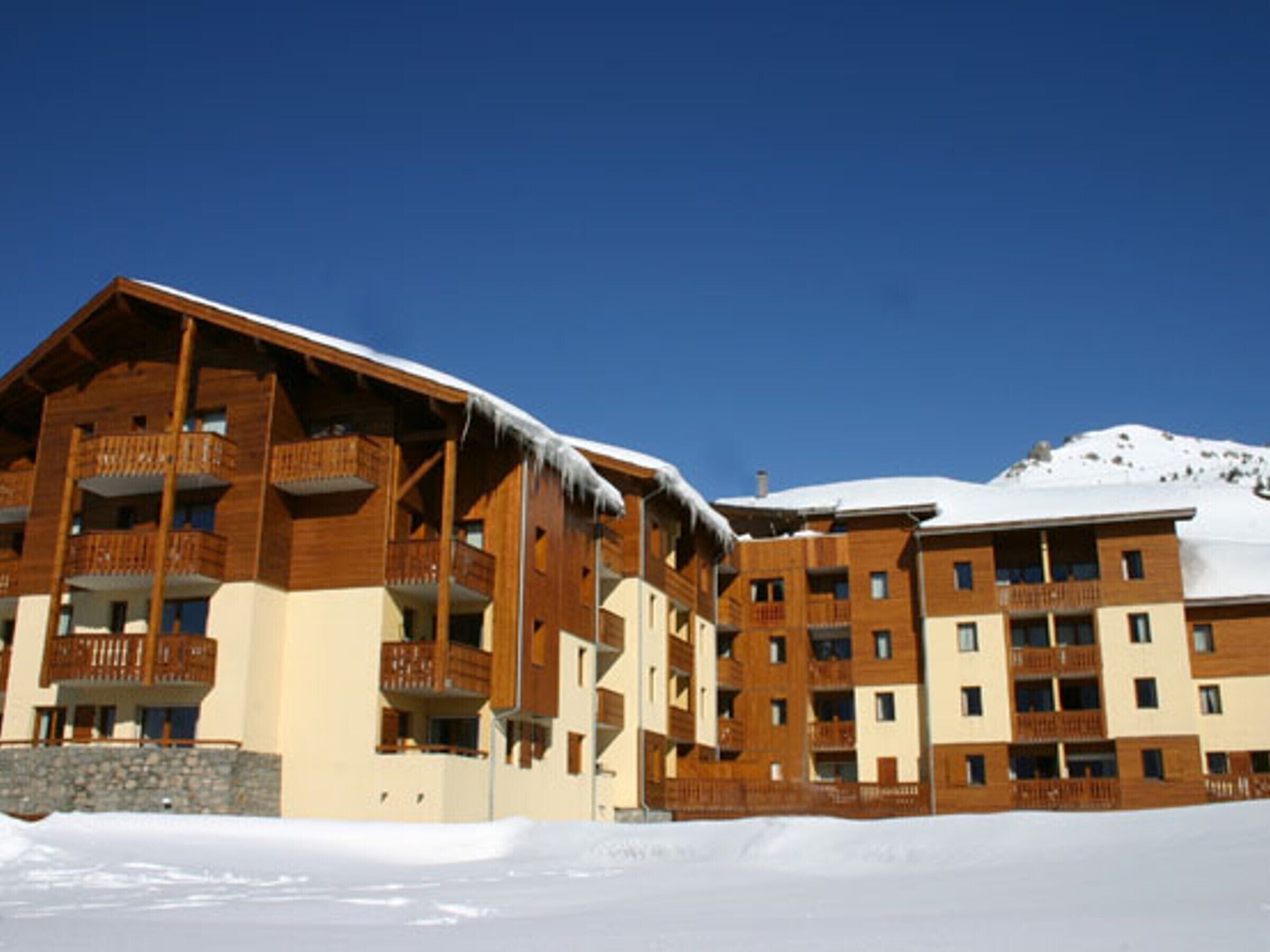 Een hotel met meerdere verdiepingen, houten balkons en een sneeuwbedekt dak.