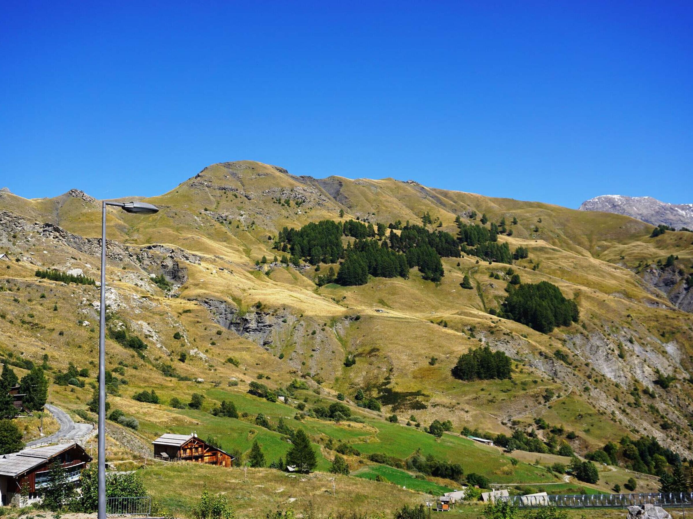 Paisaje montañoso con una cabaña de madera y un farol.