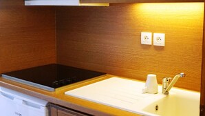 Eine kleine Küche mit Holzausstattung, einer Mikrowelle, einem Geschirrspüler und einem Spülbecken mit Wasserhahn.