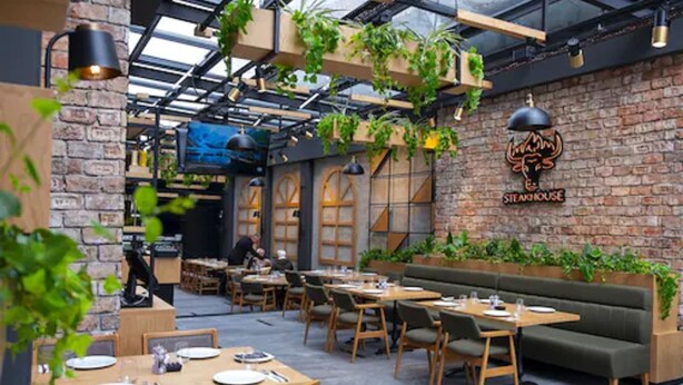 A restaurant with a brick wall, hanging plants, and a logo for 'Steakhouse'. - Serenity Comfort Hotel  (Istanbul)
