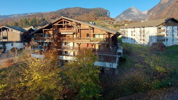 Una cabaña de madera con varios balcones, frente a un paisaje montañoso.
