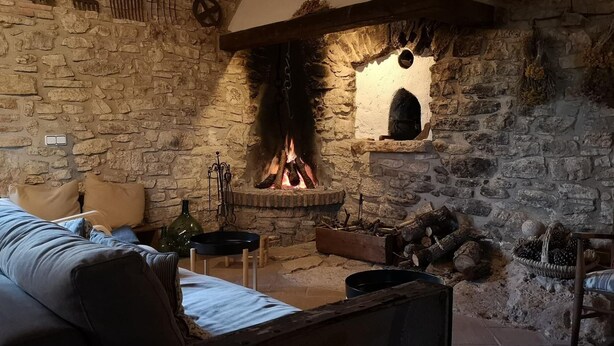 A stone-walled room with a fireplace, a sofa, and a bed. - More from lárlequí - Entire farmhouse (Rojals)