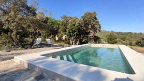 A rectangular swimming pool with clear blue water, surrounded by a pebble beach and trees. - More from lárlequí - Entire farmhouse (Rojals)