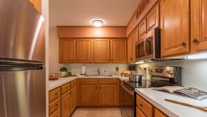 A modern kitchen with wooden cabinets, stainless steel appliances, and a white countertop.
