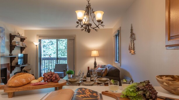 A dining area with a wooden table set for a meal, a chandelier, and a view of the outdoors.