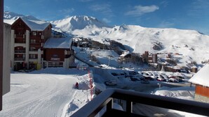A snow-covered mountain town with a ski lift, buildings, and a clear blue sky.