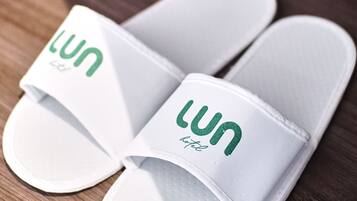 Ein Paar weiße Flip-Flops mit dem Aufdruck "lun hotel" auf einer Holzfläche.