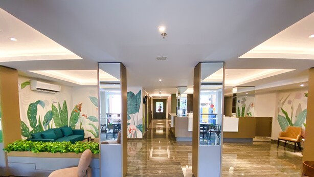 A spacious lobby with a central seating area, a reception desk, and a view into a dining area. - Lun Hotel Manado (Manado)