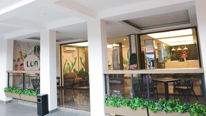 A modern interior with a reception desk, seating area, and decorative plants. - Lun Hotel Manado (Manado)