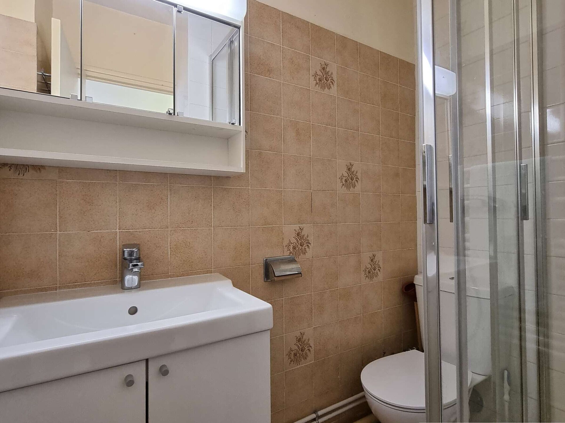 A bathroom with a white sink, a toilet, and a glass shower enclosure.