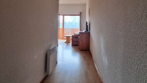 A narrow hallway with a wooden floor leading to a room with a window and a wooden table. - 2-room apartment with cabin - 6 ppl - Near slopes (Le Dévoluy)