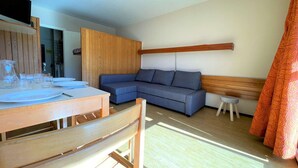 Ein modernes Wohnzimmer mit einem Holzesstisch, einem blauen Sofa und einem kleinen Hocker.
