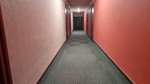 Ein Flur mit roten Wänden und Teppichboden, der zu einer Tür am Ende führt.