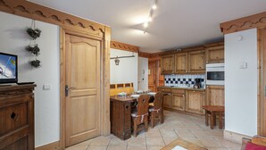 Una cocina con armarios de madera, una mesa de comedor con sillas, un banco y un televisor sobre un mueble.