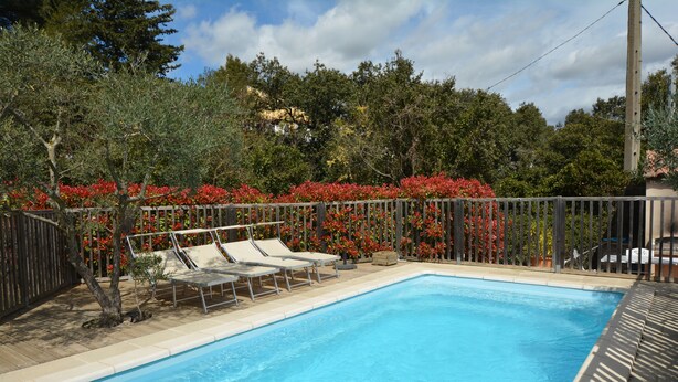 A rectangular swimming pool with a wooden deck and lounge chairs. - Charming villa with private pool in a peaceful, relaxing setting. (Comps)
