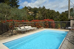A rectangular swimming pool with a wooden deck and lounge chairs. - Charming villa with private pool in a peaceful, relaxing setting. (Comps)