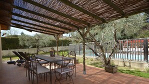 An outdoor patio with a table and chairs, a pergola, and a view of a swimming pool. - Charming villa with private pool in a peaceful, relaxing setting. (Comps)