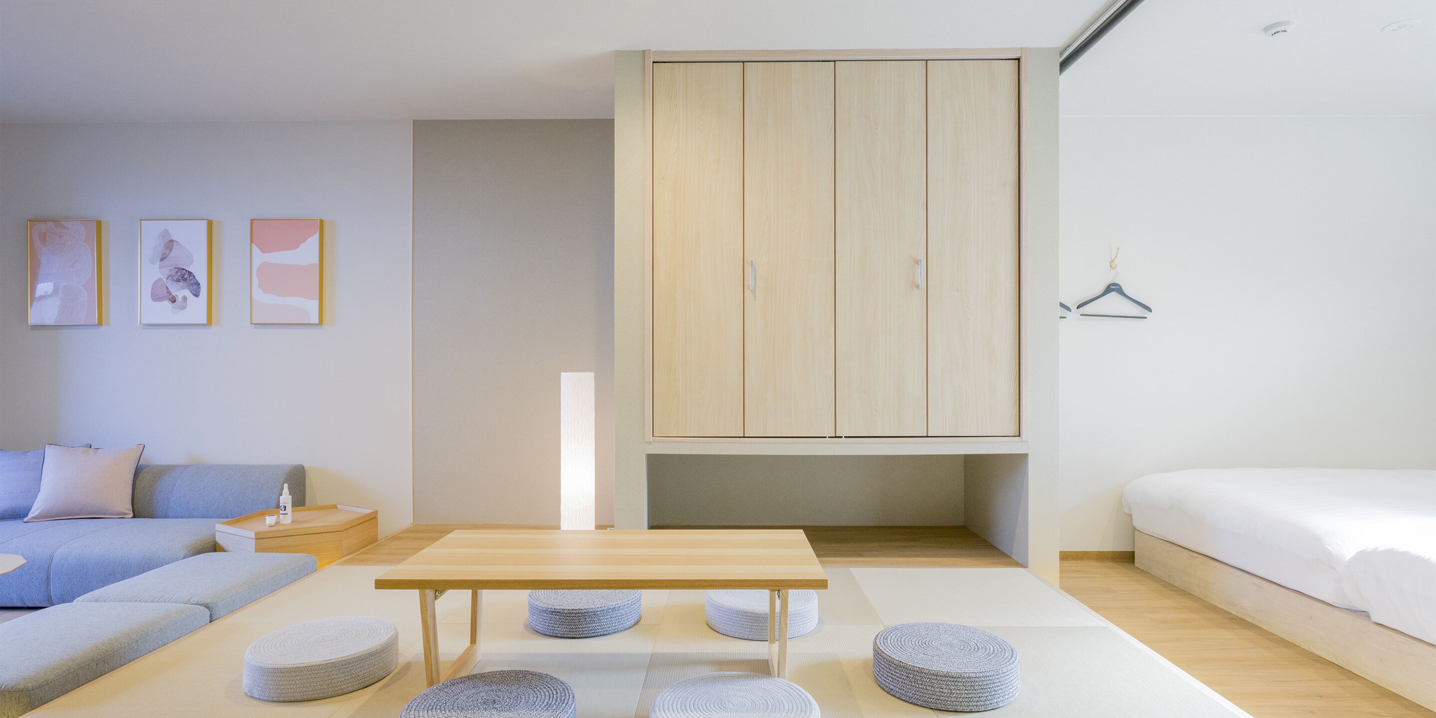 A modern bedroom with a wooden wardrobe, a sofa, a bed, and a small table.