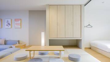 A modern bedroom with a wooden wardrobe, a sofa, a bed, and a small table.