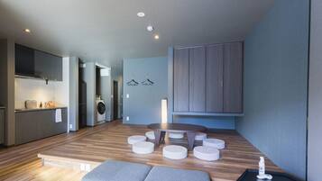 Cozinha moderna com eletrodomésticos embutidos, área de jantar com mesa redonda e pufes, e um guarda-roupa espaçoso.