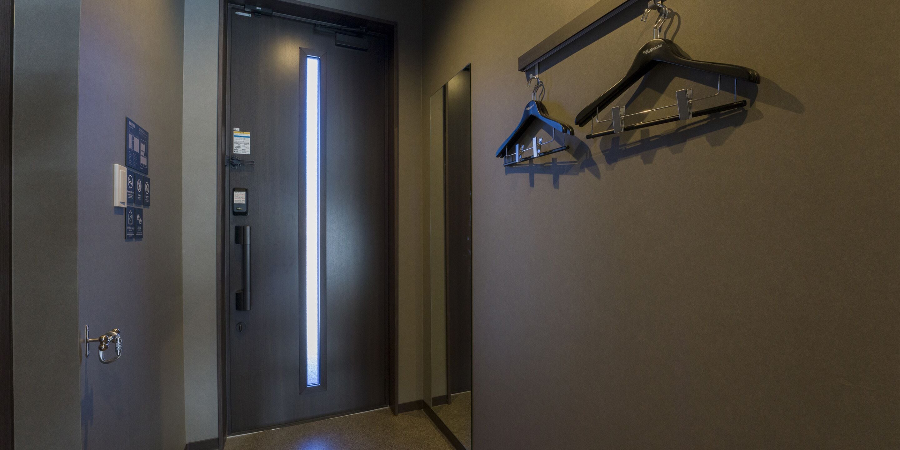 A hallway with a modern door, a coat rack, and a wall-mounted sign.