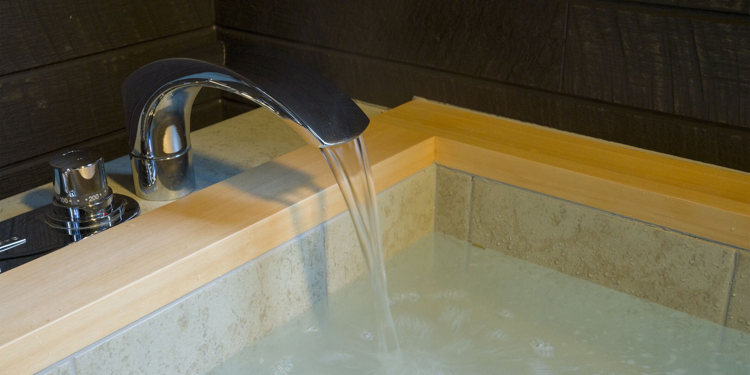 Un bagno con un lavandino moderno, un rubinetto e una vasca da bagno.