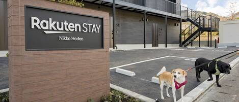 A sign for Rakuten Stay, a modern building with a wooden facade and a parking area.