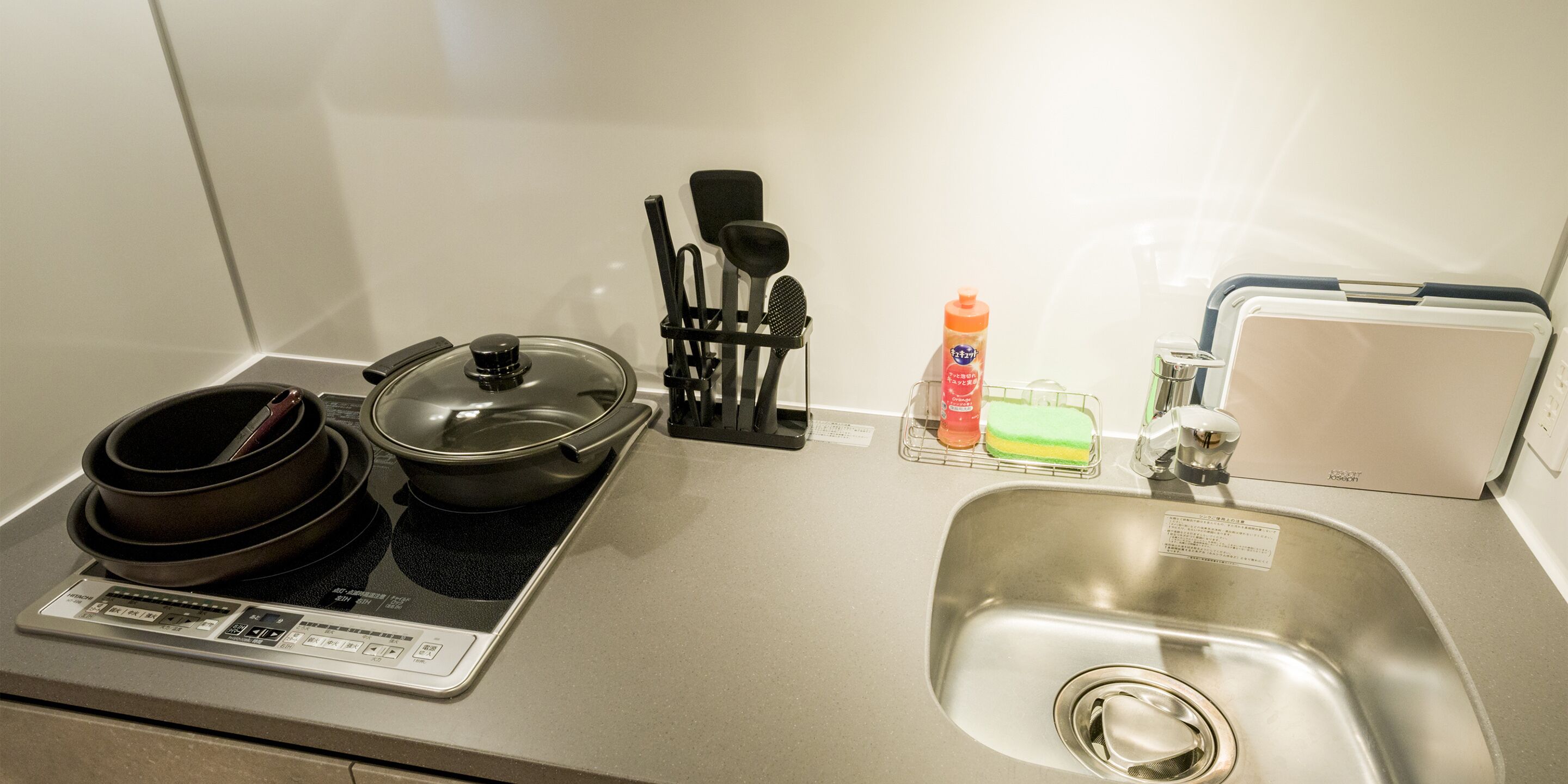 Una kitchenette equipada con estufa, ollas, un lavamanos y diversos utensilios de cocina.