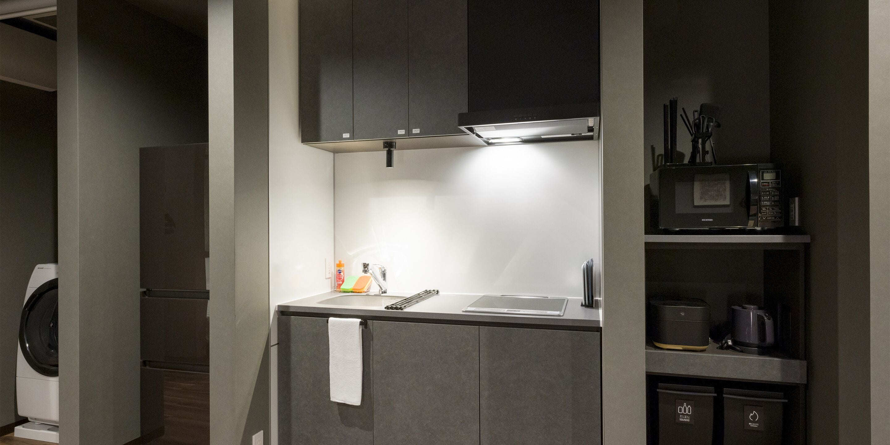 A compact kitchen with a washing machine, a microwave, and a coffee maker.